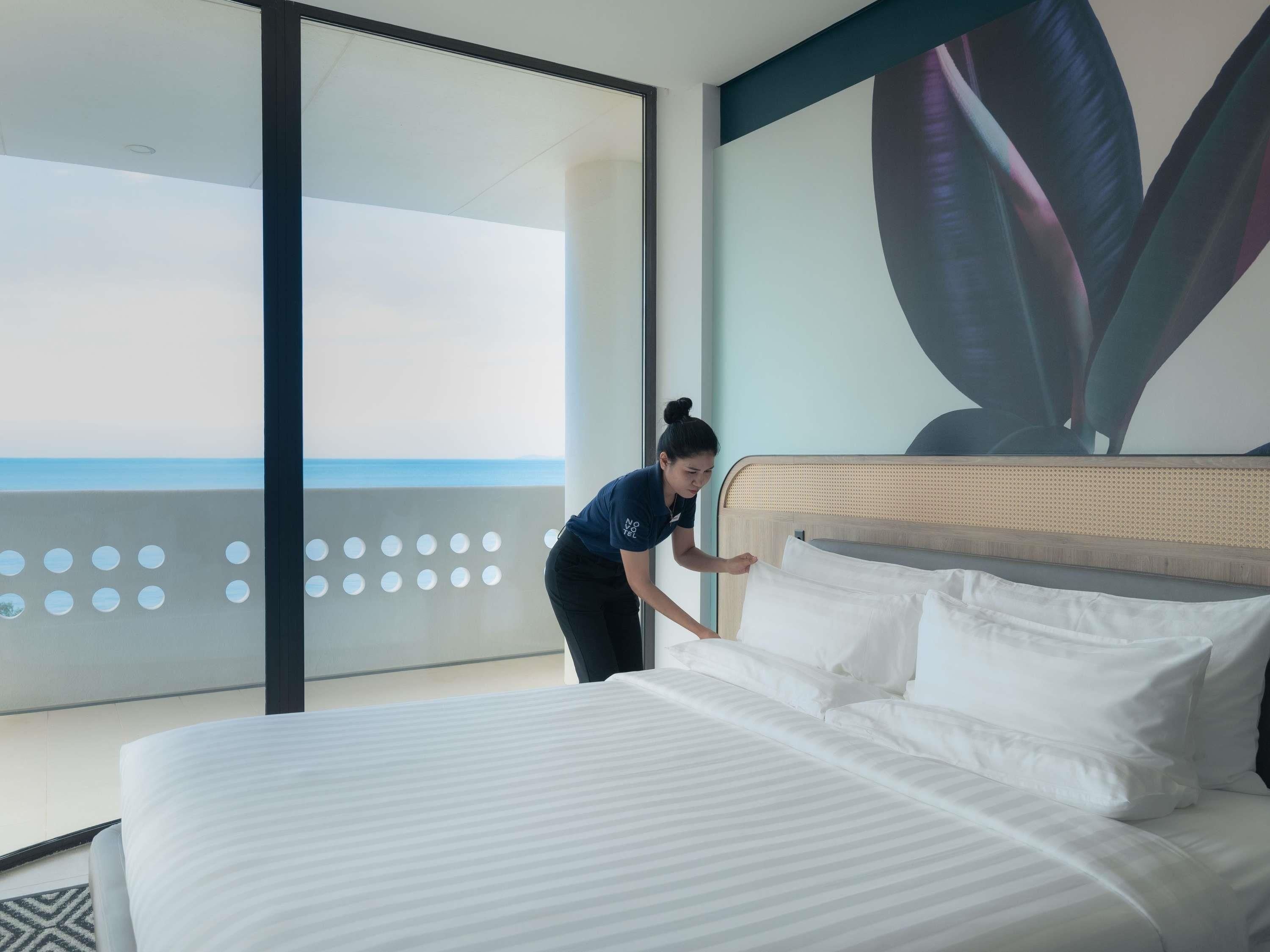 A hotel room with a bed, a large window, and a view of the ocean.