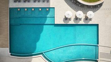 Uma piscina grande com um deck ladrilhado, rodeada por espreguiçadeiras e guarda-sóis.
