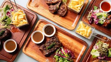 A variety of dishes including steaks, fries, and salads on wooden serving boards.