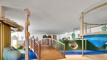 A play area with a wooden bridge, a slide, and a netted climbing structure.
