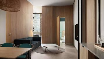 A modern interior with a dining area, sofa, round coffee table, and a kitchen area with a TV.