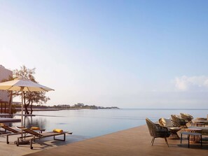 Un espace aménagé au bord de la piscine, avec des chaises longues, une table et un parasol.