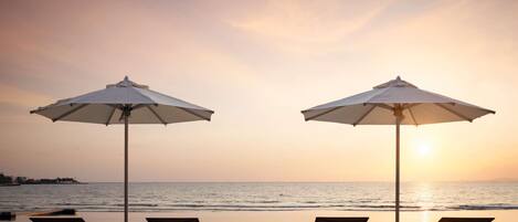 Eine Strandterrasse mit Liegestühlen und Sonnenschirmen mit Blick auf den Ozean.
