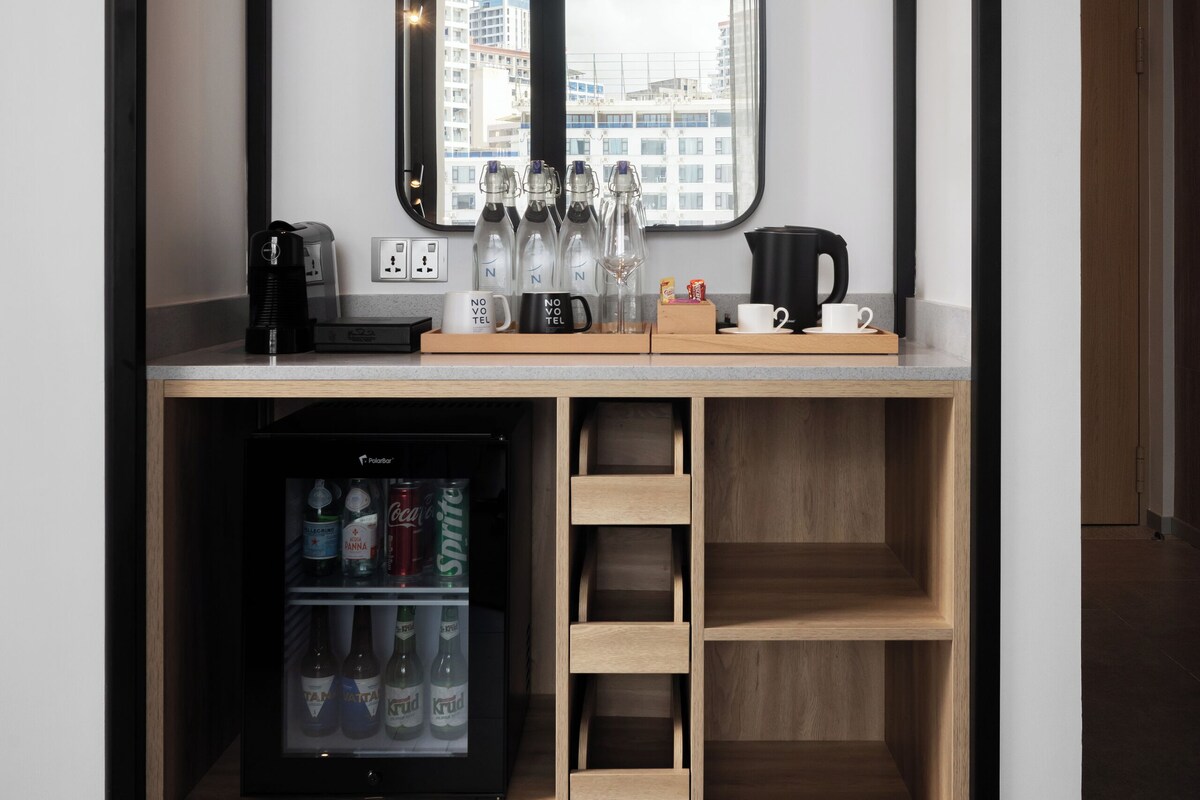 Una kitchenette moderna con un refrigerador empotrado, una cafetera y una vitrina de vidrio.