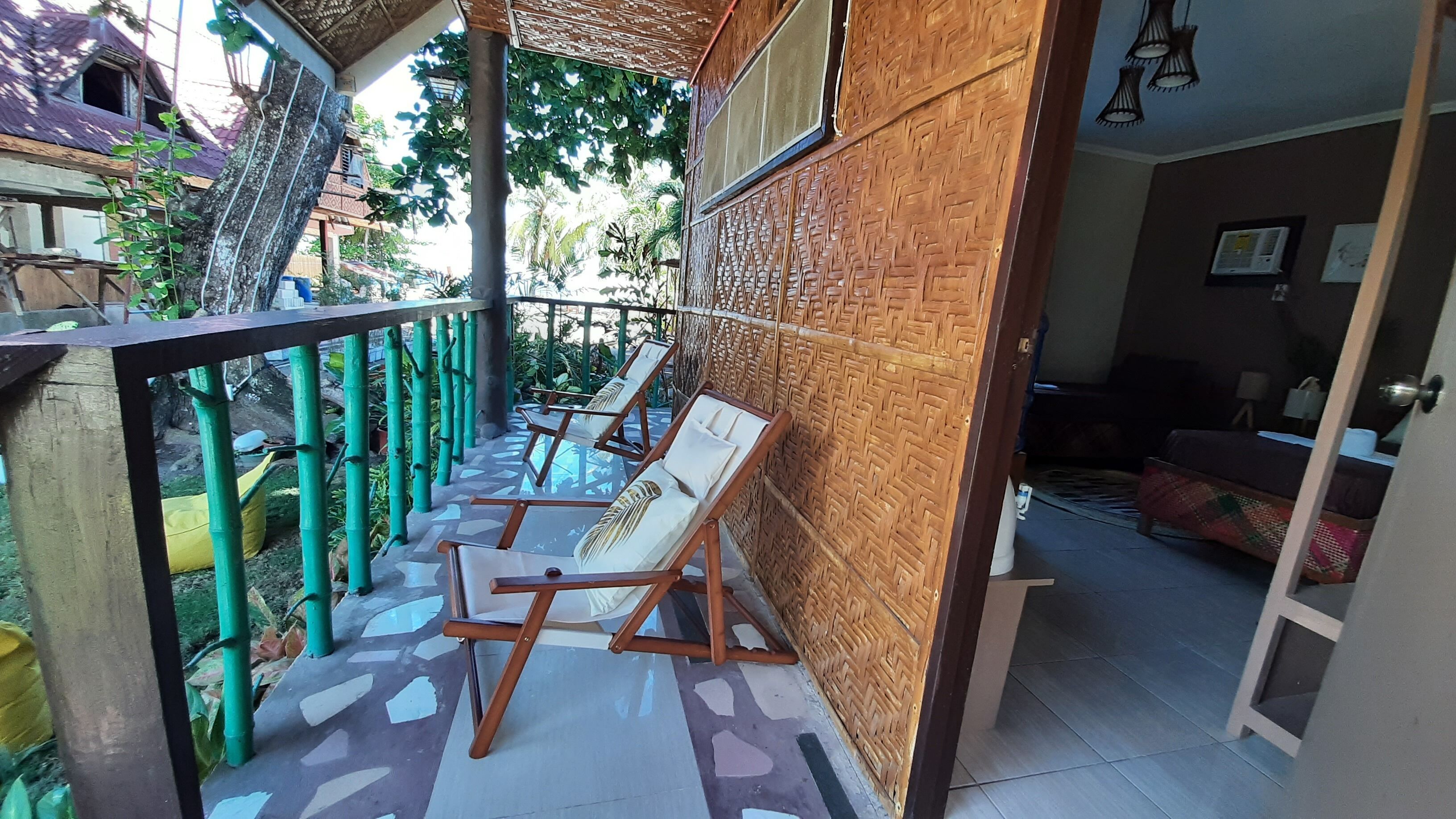 Un balcon avec deux chaises longues, un sol à motifs et une vue sur un immeuble dont le toit est violet.