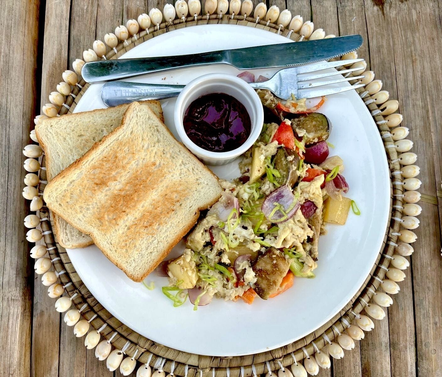 Un piatto con pane tostato, un'insalata e una piccola ciotola di salsa su un tavolo di legno.