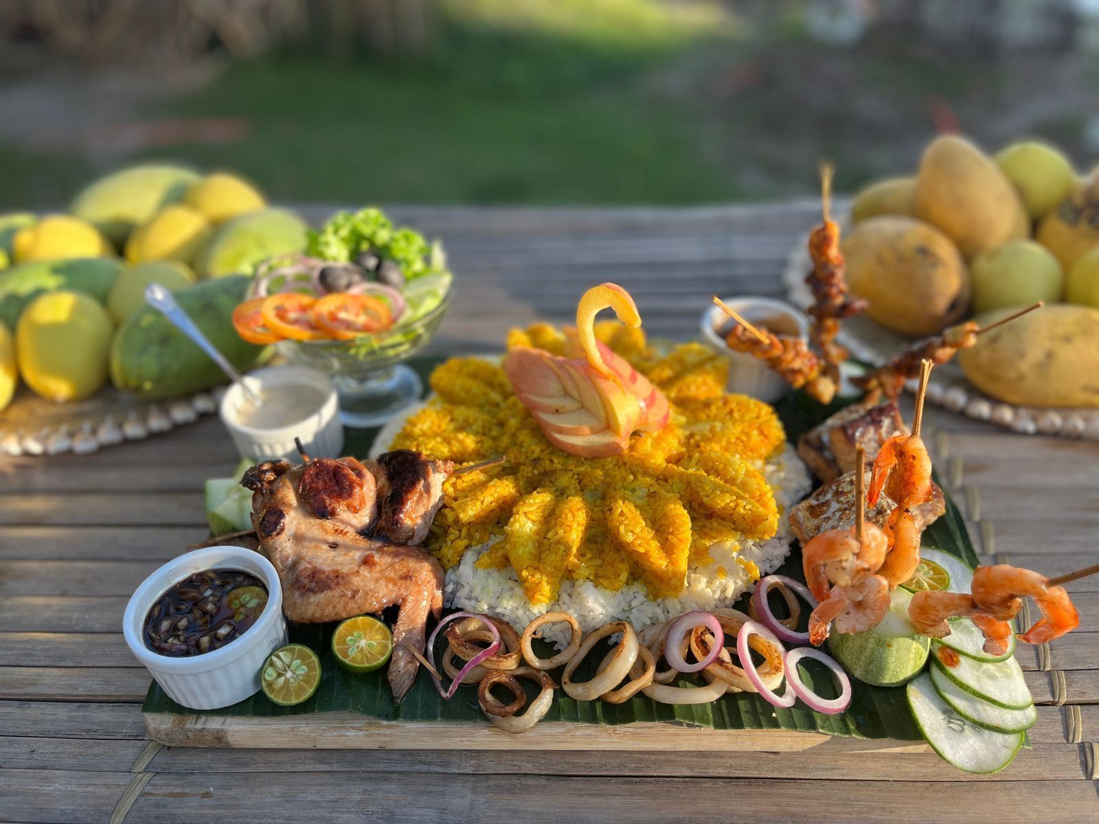 A table with a variety of dishes including rice, grilled meat, shrimp, and vegetables.