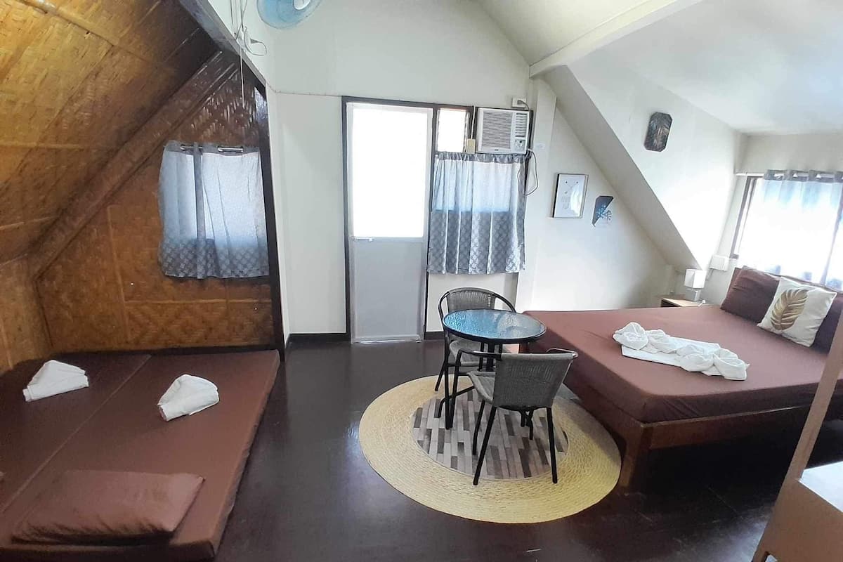 A compact room with a bed, a small table, and two seating areas.