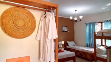 A room with two beds, a hanging chair, a woven mat, and a framed picture on the wall.