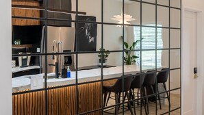 Et moderne køkken med en central ø, sort rumdeler og et spiseområde med stole.