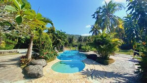 A swimming pool surrounded by tropical plants and palm trees.