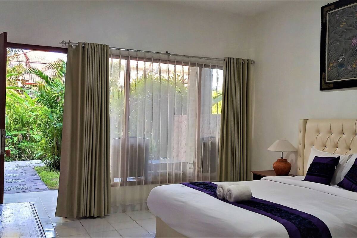 A hotel room with a bed, a nightstand, a lamp, and a painting on the wall.