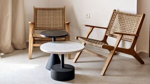 A room with two wicker chairs, a round table, and a wall-mounted lamp. - Alexandra Beach Hotel (Chania)