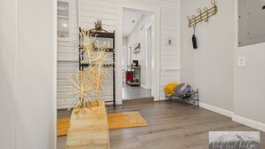 A modern interior with a wooden bench, a decorative vase, and a hallway leading to a kitchen area. - Single Family Home with Fenced Backyard and AC! (Philomath)