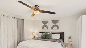 A bedroom with a bed, a ceiling fan, a nightstand with a lamp, and a small table with a plant. - Single Family Home with Fenced Backyard and AC! (Philomath)