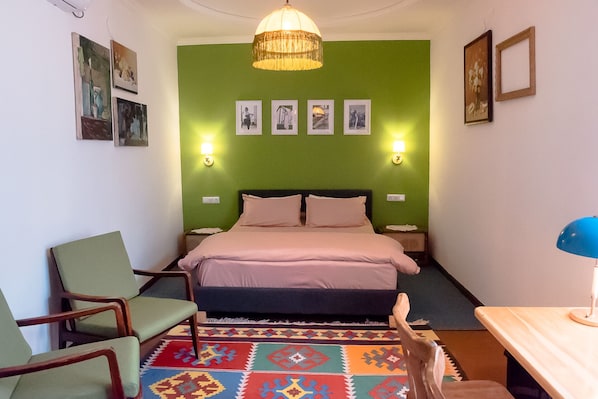 Une chambre à coucher avec un lit, deux lampes de chevet, un mur vert et un tapis à motifs.