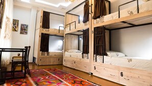 A dormitory room with bunk beds, a desk, and a colorful rug. - Old Radio  (Samarkand)