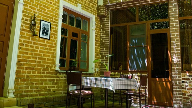 A brick building with a covered patio area, a table with chairs, and a door. - Old Radio  (Samarkand)