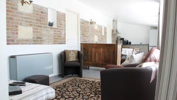 A living room with a brick wall, a radiator, a sofa, a chair, and a coffee table.