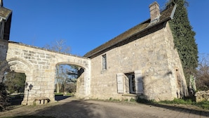 A stone building with an arched entrance, a wooden bench, and a cobblestone pathway. - Le Translon  (Saint-Pierre-Aigle)