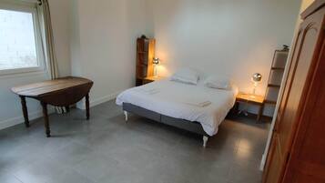 Un dormitorio con cama, mesitas de noche, escritorio y silla.