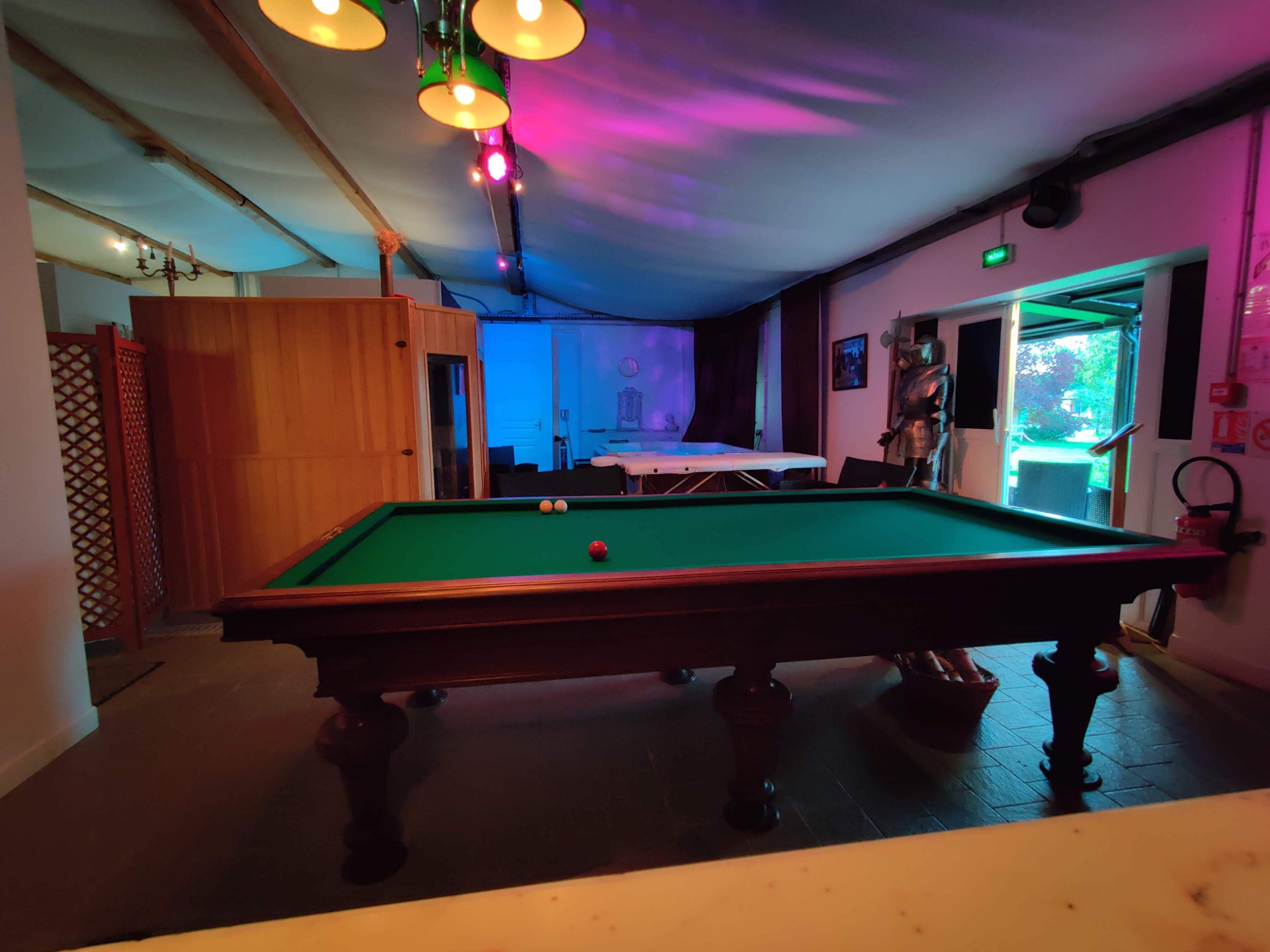 A pool table with balls, a wooden door, and a room with a view of the outdoors.