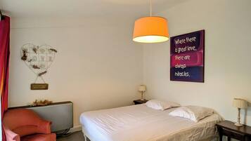 A bedroom with a bed, a chair, a wall-mounted lamp, and a motivational quote on the wall.