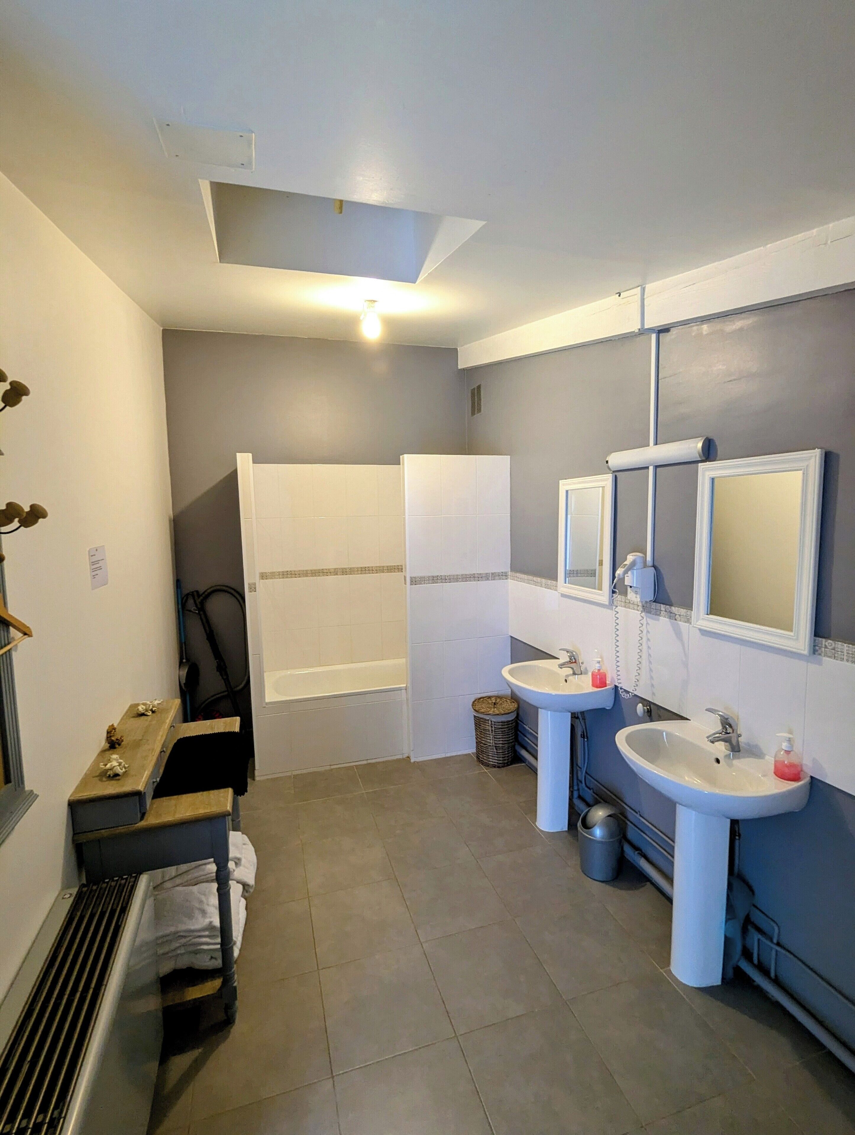 A bathroom with a bathtub, two sinks, a mirror, and a heater.