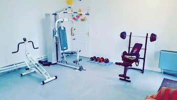 Un gimnasio con equipo de ejercicio, incluyendo una cinta de correr, banco de pesas y mancuernas.