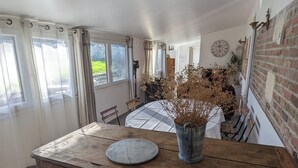 A rustic kitchen with a wooden island, a dining table, and a brick wall. - Le Translon  (Saint-Pierre-Aigle)