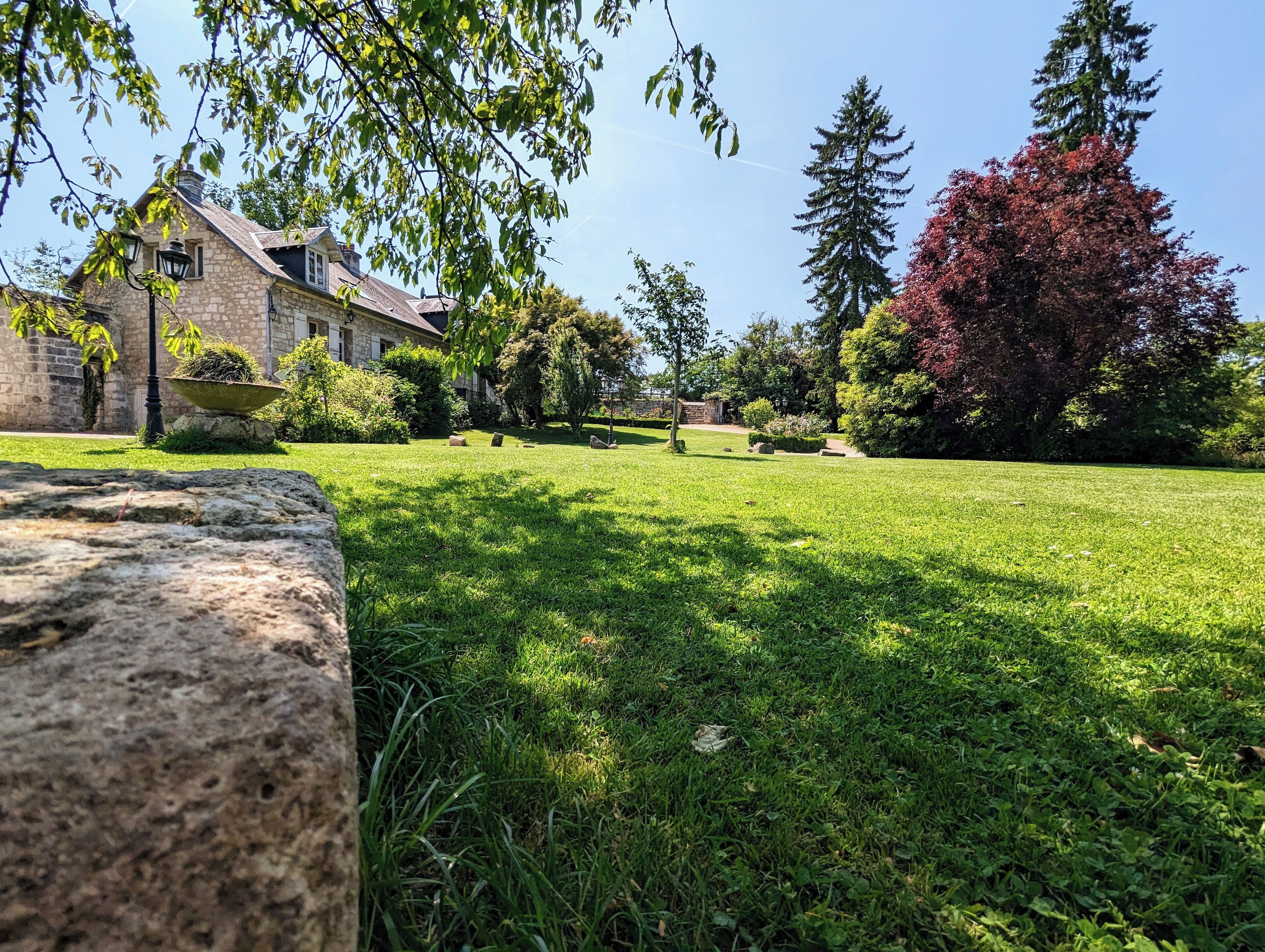 A stone building with a stone facade and a large window, surrounded by a well-maintained lawn and trees.