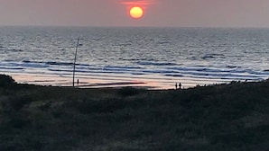 A sunset over the ocean with a beach in the foreground.