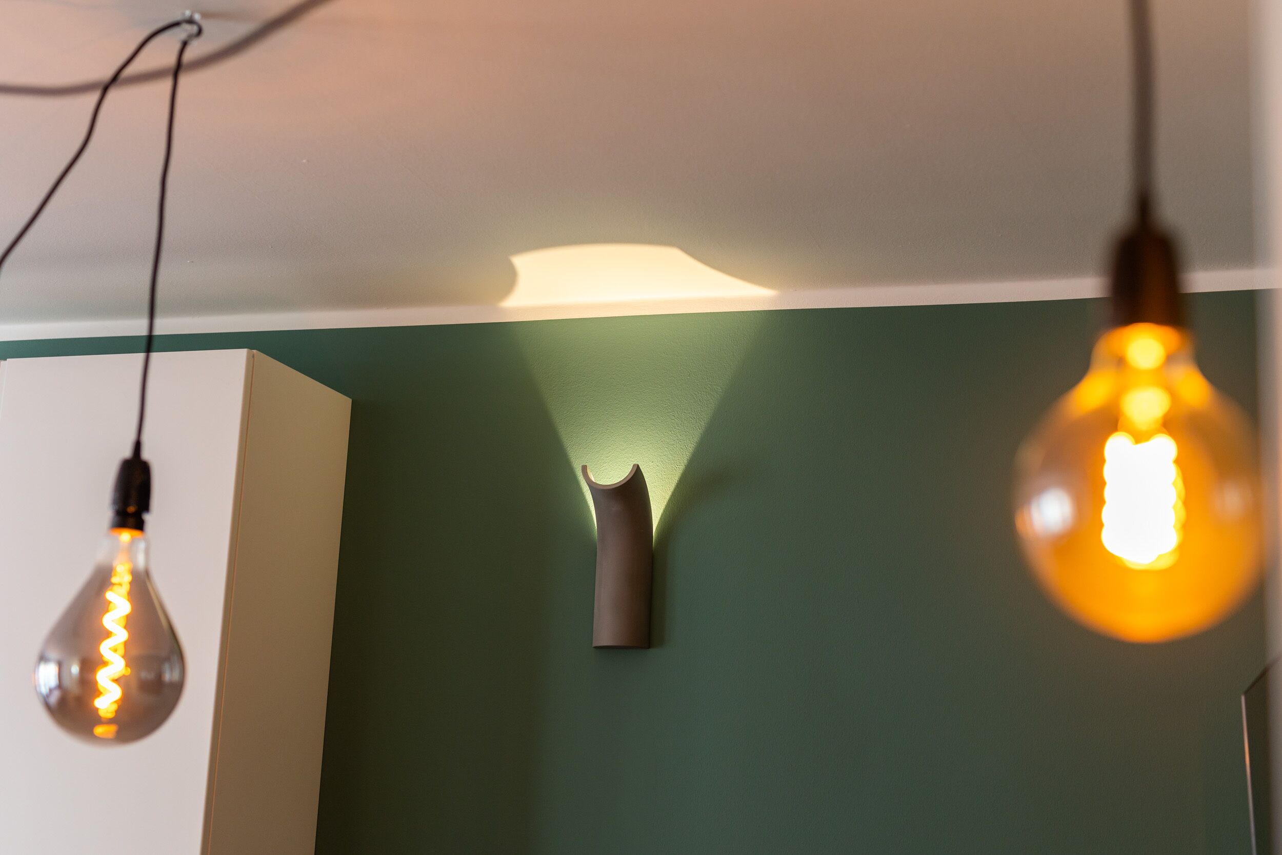 Three light fixtures against a green wall.