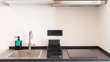 A modern kitchen with a stainless steel sink, a black soap dispenser, and a black appliance on the counter.