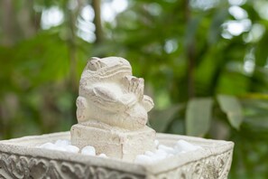 Una escultura de piedra de una figura dentro de un cuenco decorativo.