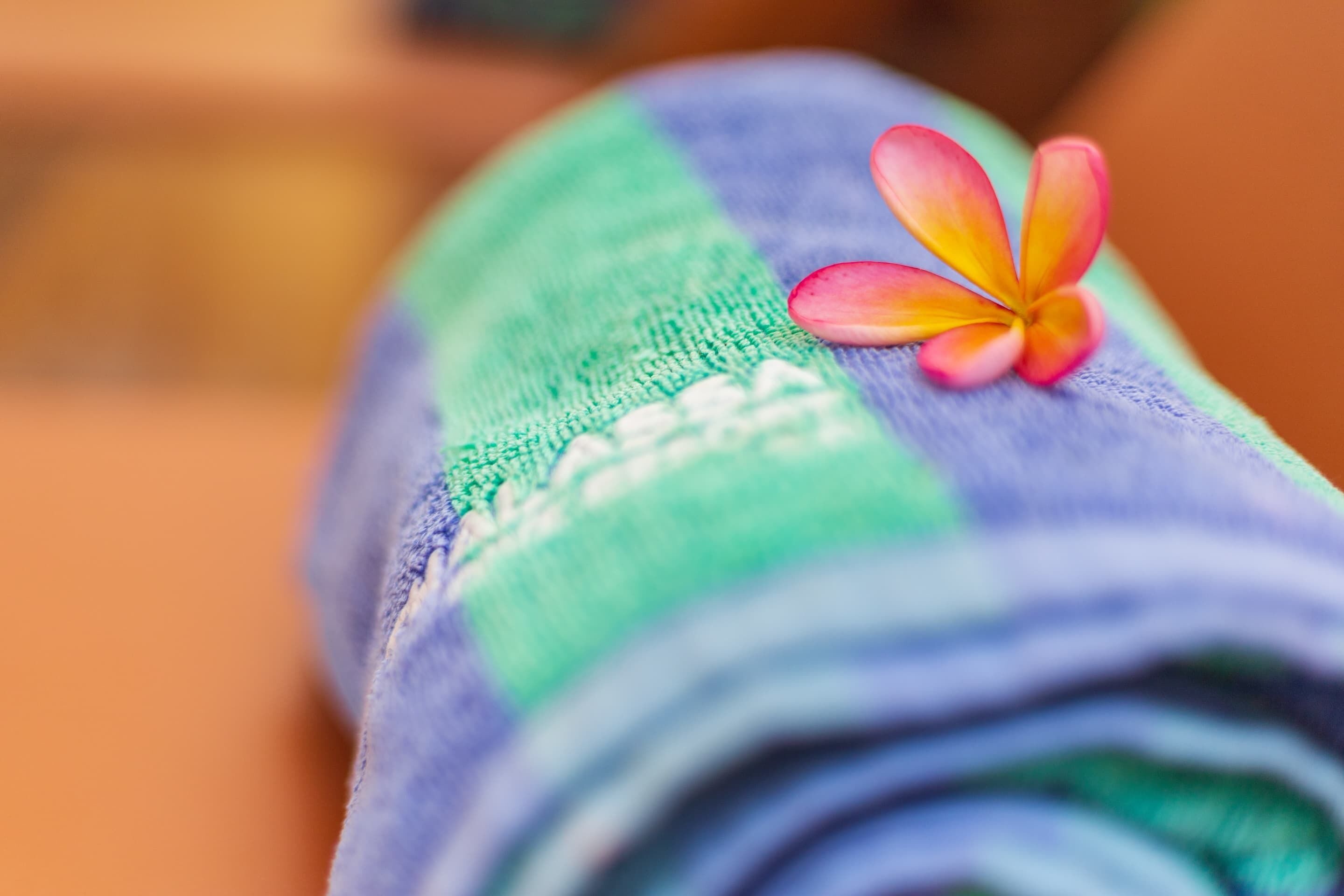 A rolled-up towel with a flower on it.