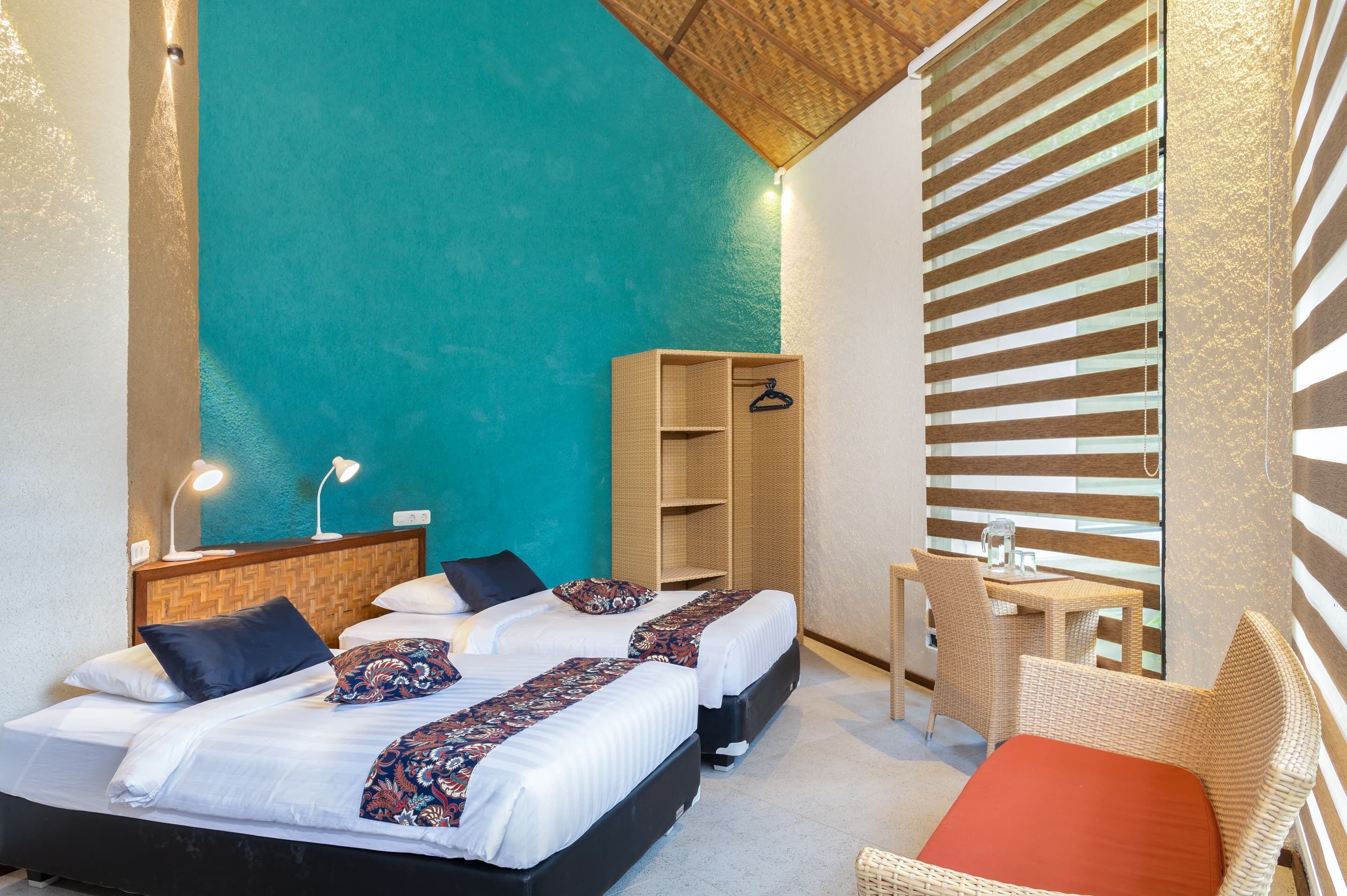 Una habitación de hotel con dos camas, una mesita, una silla y un armario.