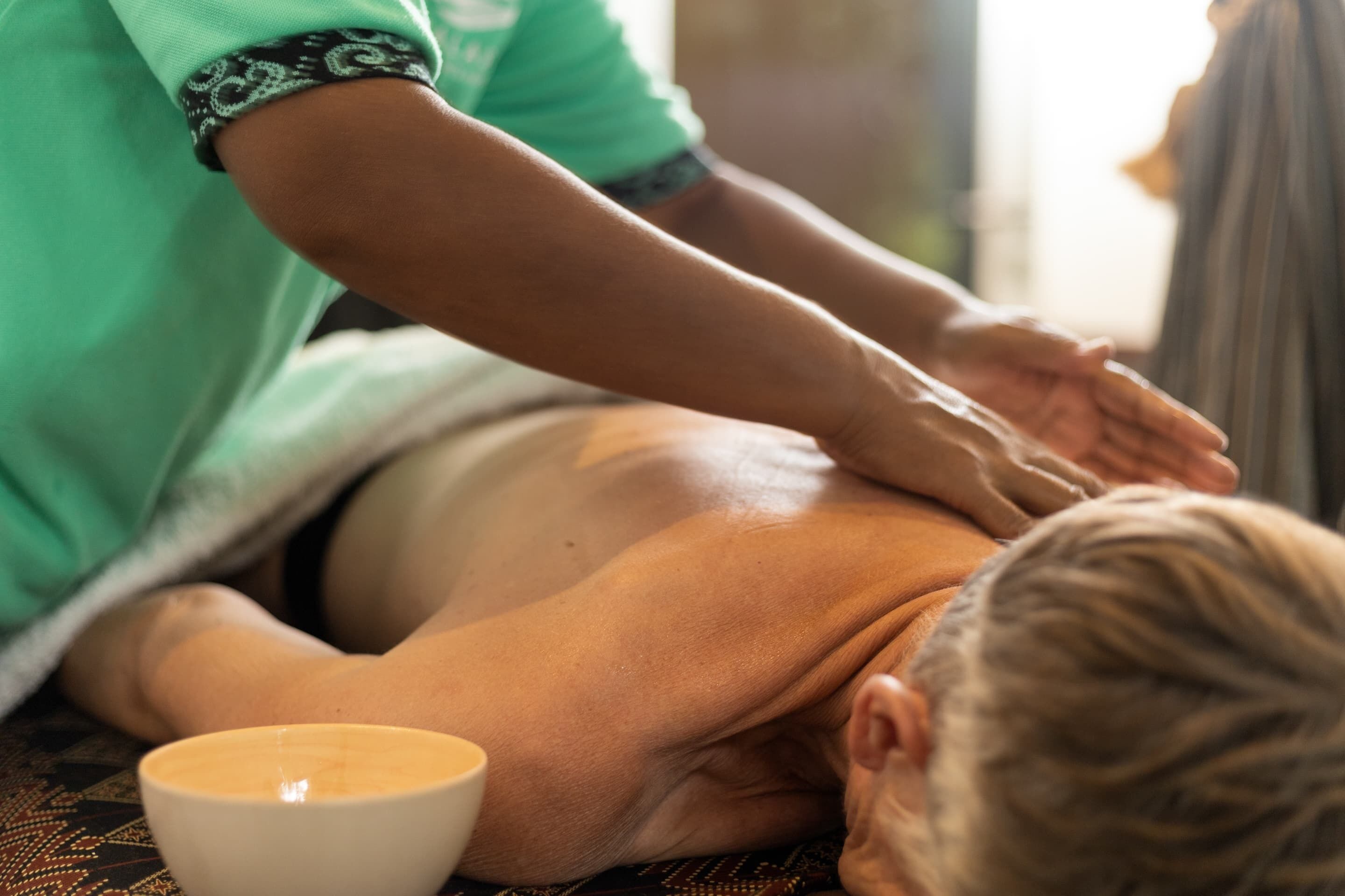 Une personne reçoit un massage, une tasse de thé étant posée sur la table.