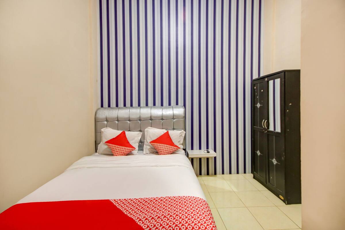 Ein Hotelzimmer mit Bett, Nachttisch, Kleiderschrank und einer gestreiften Wand.