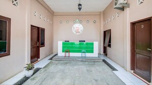 A hallway with a reception desk, two stools, and a potted plant. - Hotel O Sonya Homestay Syariah (Tebing Tinggi)