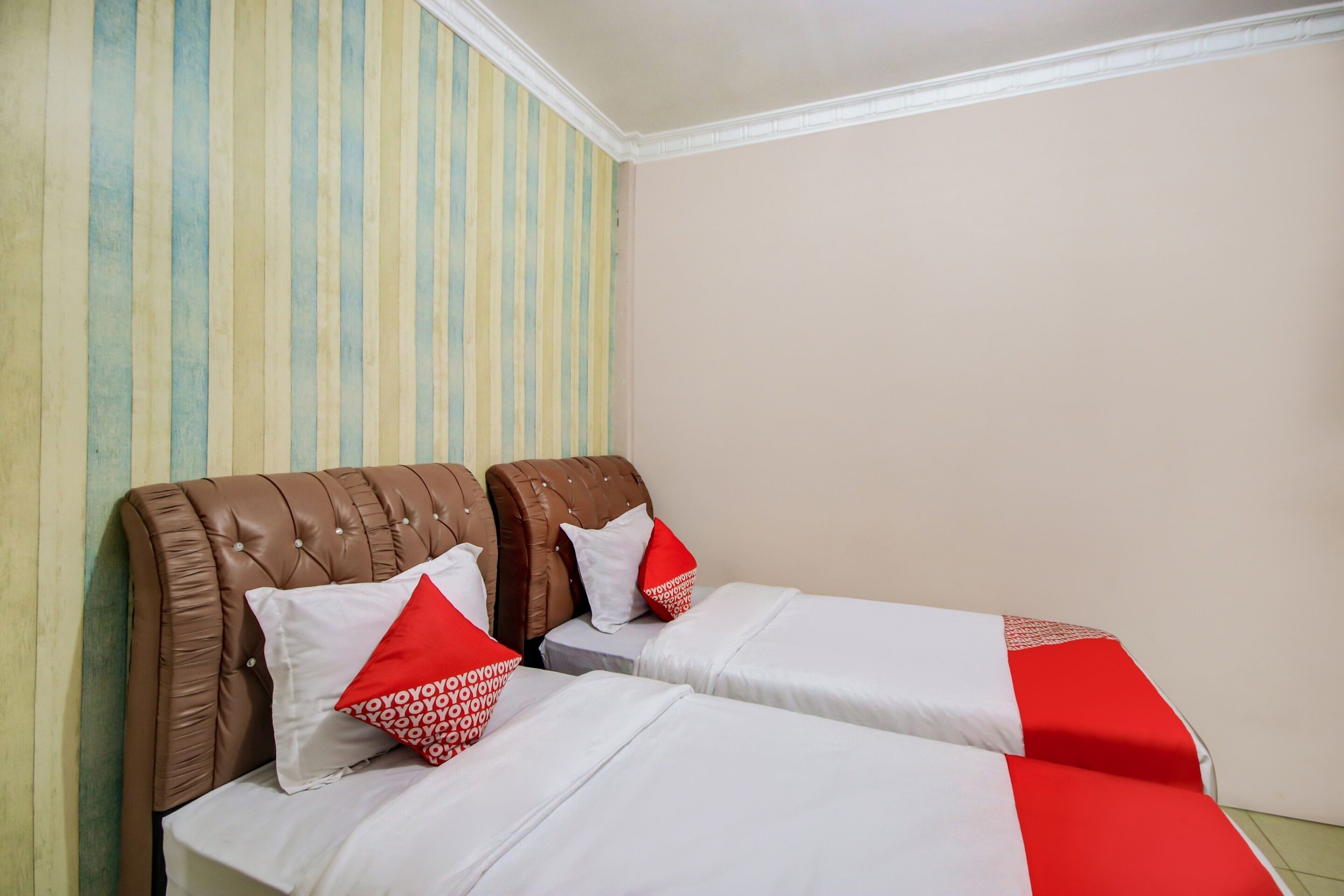 Een kamer met twee bedden, gestreept behang en een effen muur.