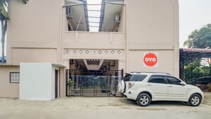 A building with a beige facade, a black gate, and a white car parked in front. - Hotel O Sonya Homestay Syariah (Tebing Tinggi)