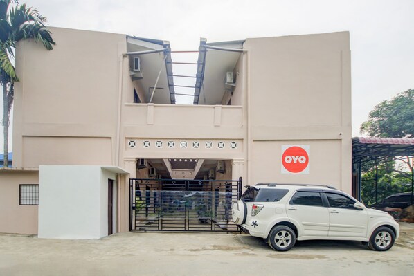 A building with a beige facade, a black gate, and a white car parked in front.