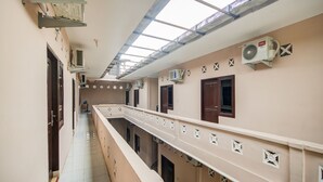 A corridor with a skylight, air conditioning units, and a long balcony with decorative elements. - Hotel O Sonya Homestay Syariah (Tebing Tinggi)