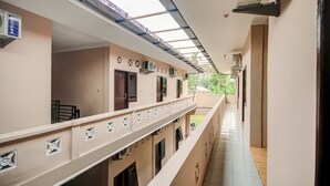 A corridor with a tiled floor, a balcony with a railing, and multiple doors and windows on the walls. - Hotel O Sonya Homestay Syariah (Tebing Tinggi)