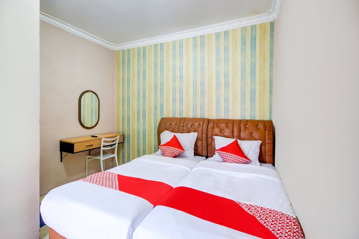 Ein Hotelzimmer mit einem großen Bett, einem Holzkopfstück, einem Schreibtisch mit Stuhl und einer gestreiften Wand.