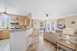 A modern kitchen with white cabinets, a built-in oven, and a dining area with a white table and chairs.