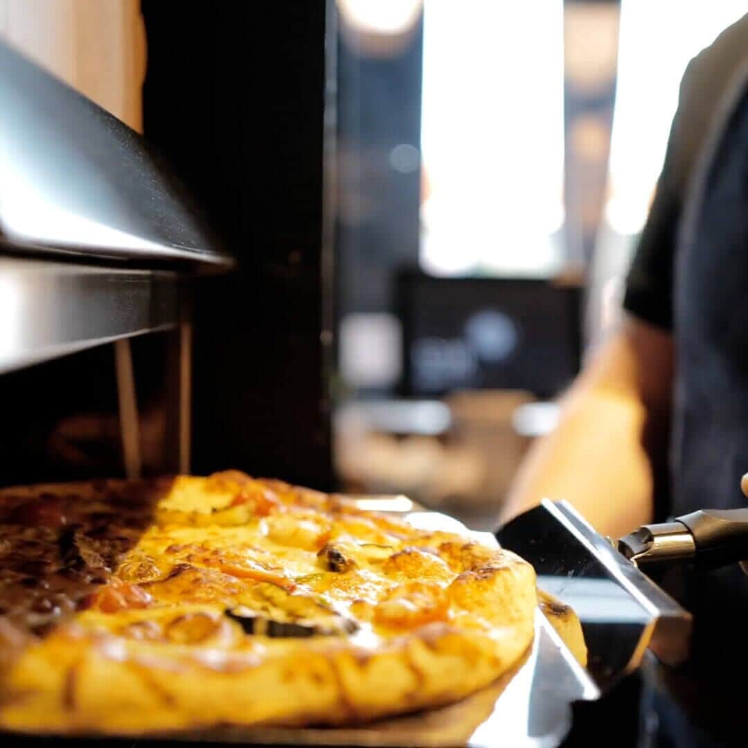 Une pizza en cours de préparation dans une cuisine industrielle.