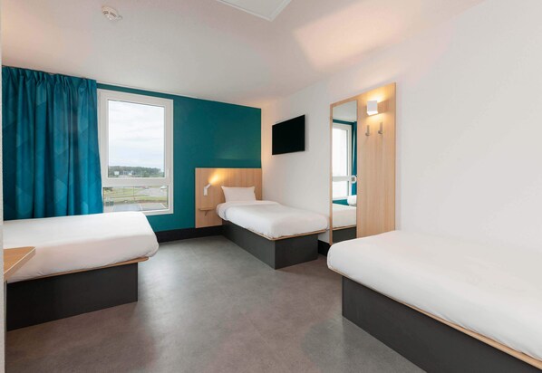 A hotel room with two single beds, a large window, a flat-screen TV, and a mirror.
