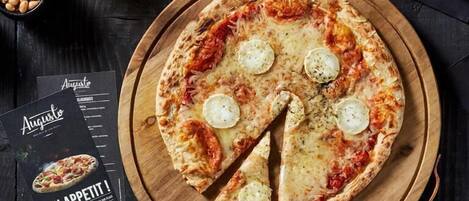 Una pizza sobre una tabla de madera con un cortador de pizza y un menú al lado.